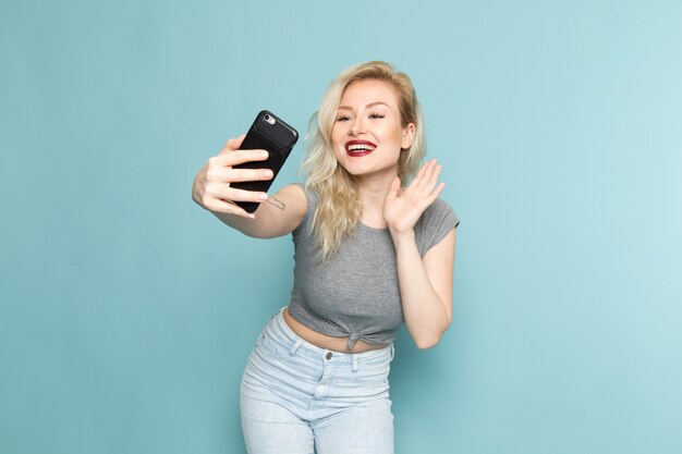 female in grey shirt and bright blue jeans taking a selfie