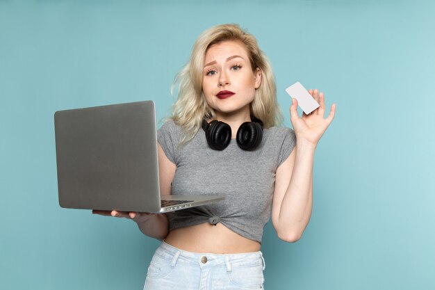 female in grey shirt and bright blue jeans using laptop