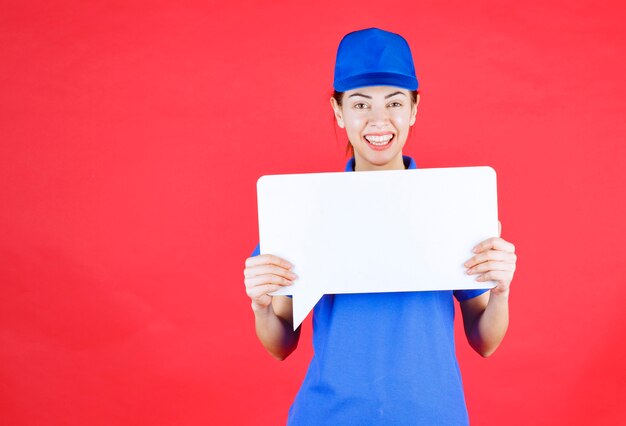 Female guide in blue uniform holding a white rectangular info board. 