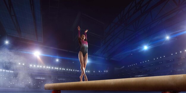 Female gymnast doing a complicated trick on gymnastics balance beam in a professional arena