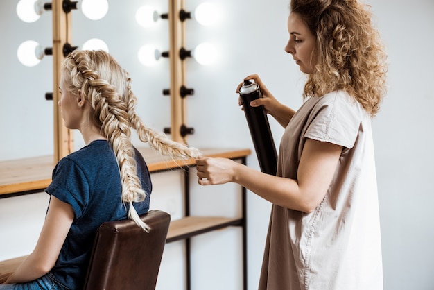ビューティーサロンで金髪の女性に髪型を作る女性美容師