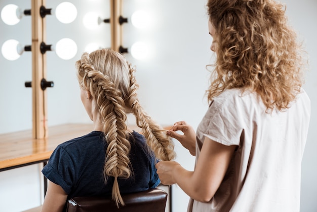 Free photo female hairdresser making hairstyle to blonde woman in beauty salon