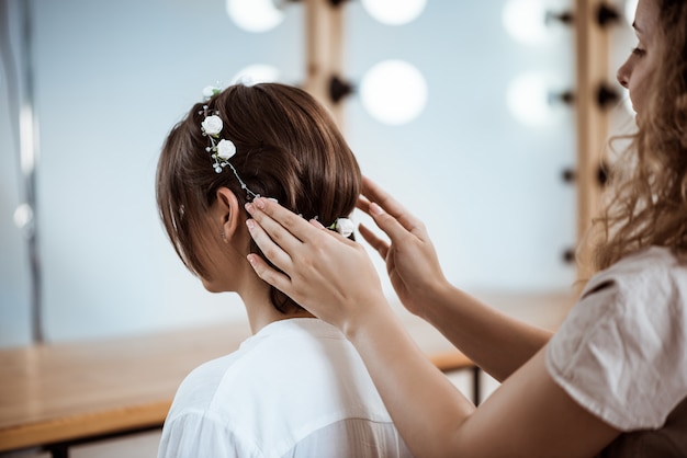 Женский парикмахер делает прическу для брюнетки в салоне красоты