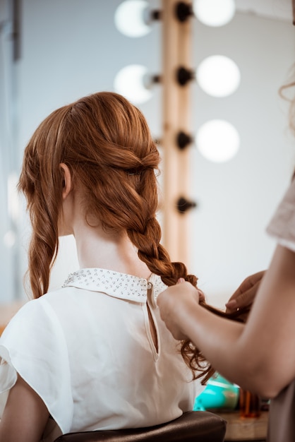 Foto gratuita parrucchiere femminile che fa acconciatura alla donna di redhead nel salone di bellezza