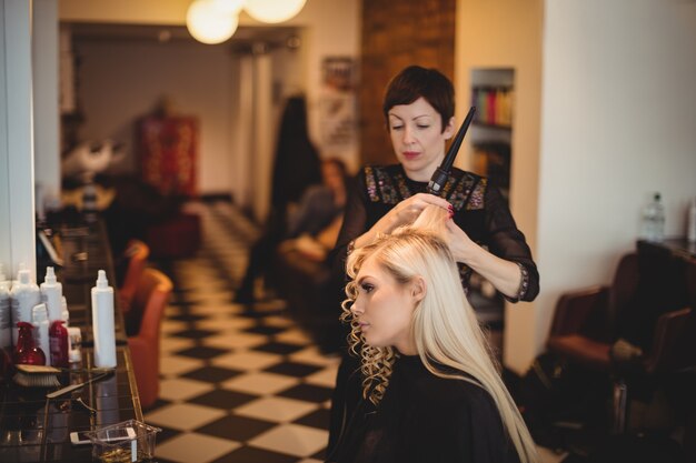 クライアントの髪をスタイリングする女性の美容師