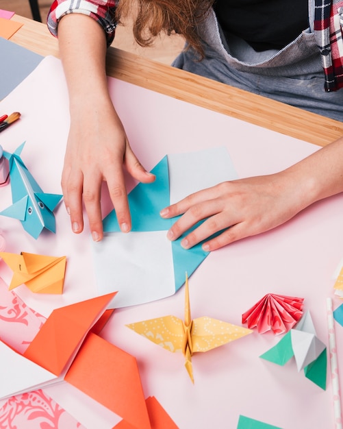 Female hand folding paper while making decorative origami art craft