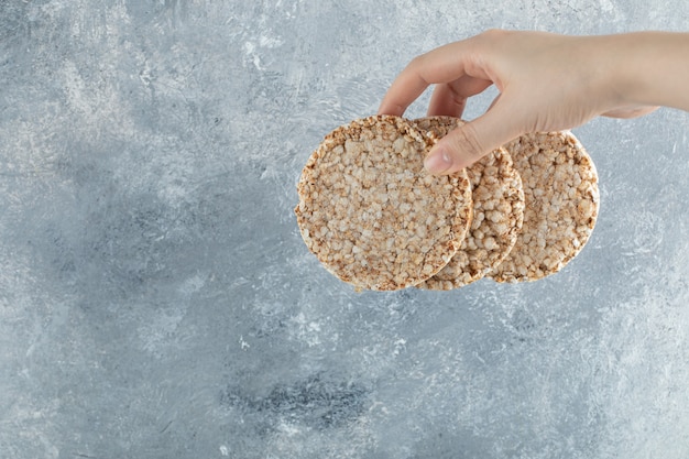 Mano femminile che tiene arioso pane croccante sulla superficie di marmo