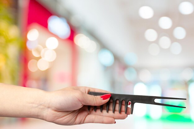 Female hand holding barber comb in cosmetic store