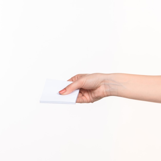 Женская рука держит чистый лист бумаги для записей на белом фоне с правой тенью