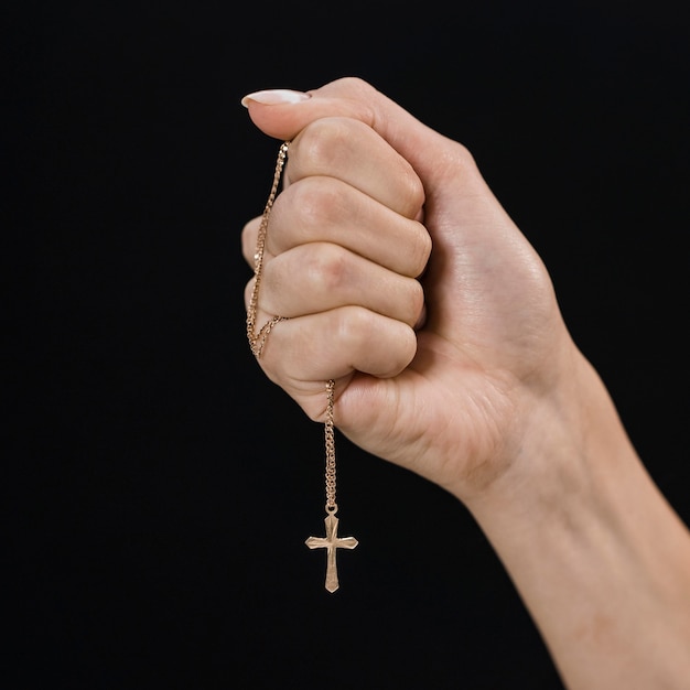 Женская рука держит крест ожерелье