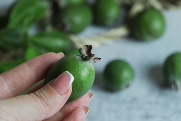 Free photo female hand holding green feijoa fruit.