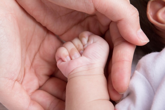 生まれたばかりの赤ちゃんの手を握って女性の手