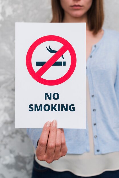 female hand holding paper with no smoking massage