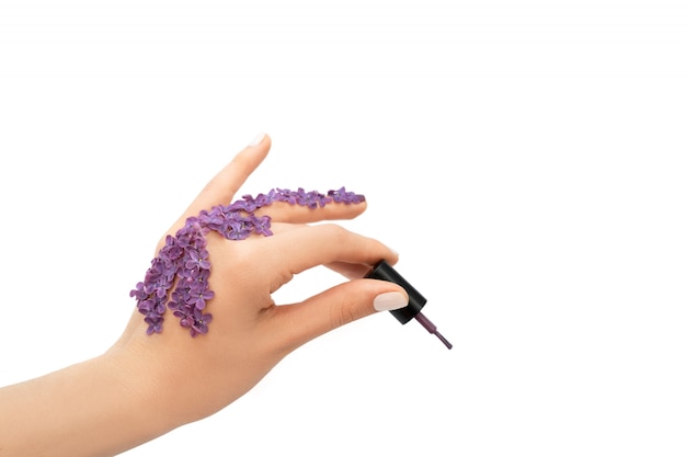 Female hand holding purple nail polish bottle. Spring concept.