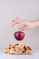 Female hand holding red ripe apple over stone