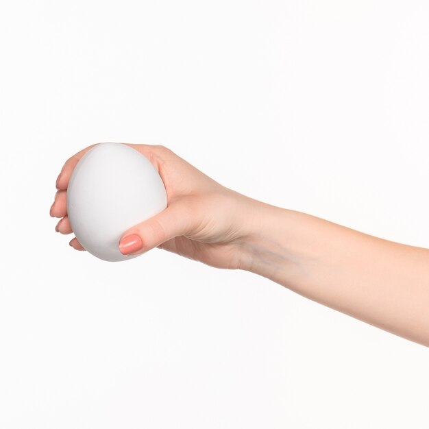 The female hand holding white blank styrofoam oval against the white background  with right shadow