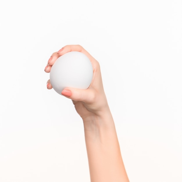 female hand holding white blank styrofoam oval against the white background with right shadow