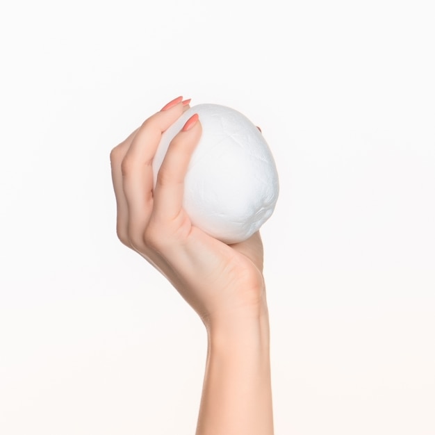 female hand holding white blank styrofoam oval against the white background with right shadow