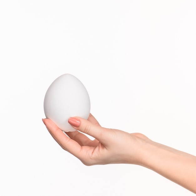 female hand holding white blank styrofoam oval against the white background with right shadow