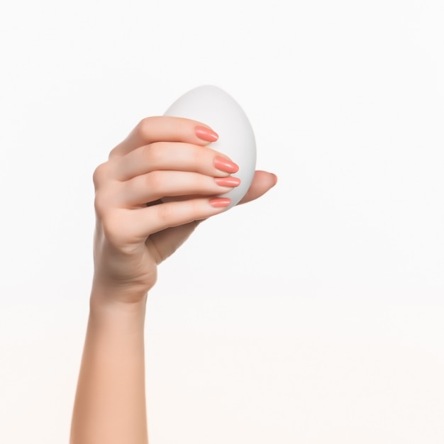 白い空白の発泡スチロールの楕円形を持っている女性の手