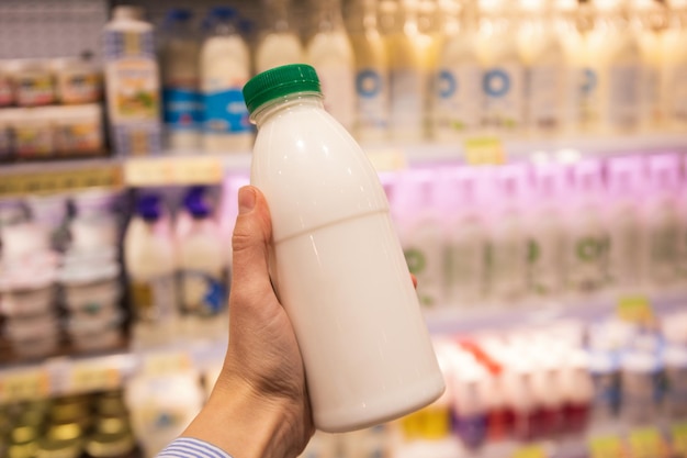 Free photo female hand holds blank bottle of dairy product