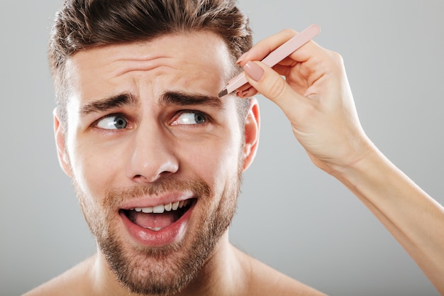 Free photo female hand plucking scared men's eyebrows