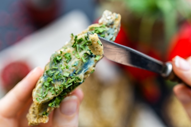 Free photo female hand putting onion on a raw vegan bread with a knife