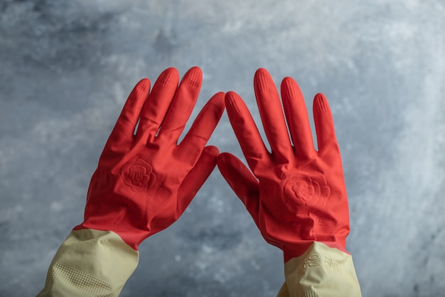 Female hand in red protective gloves on marble.