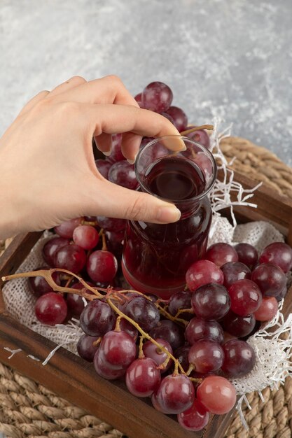 Female hand taking glass of juice from wooden box. 