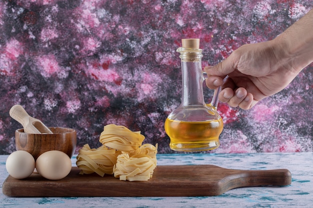 Female hand taking oil bottle from wooden board.