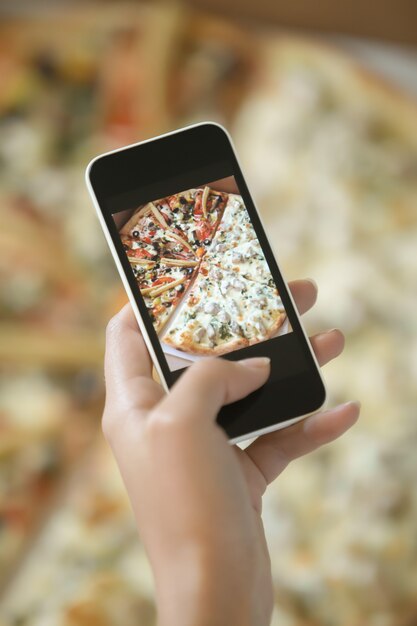 Female hand taking a picture of pizza