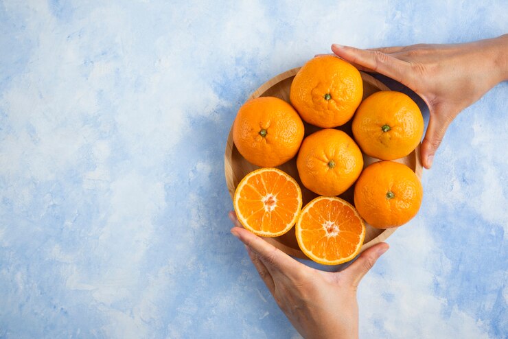 Free Photo female hand taking slice from pile. clementine mandarins on blue surface