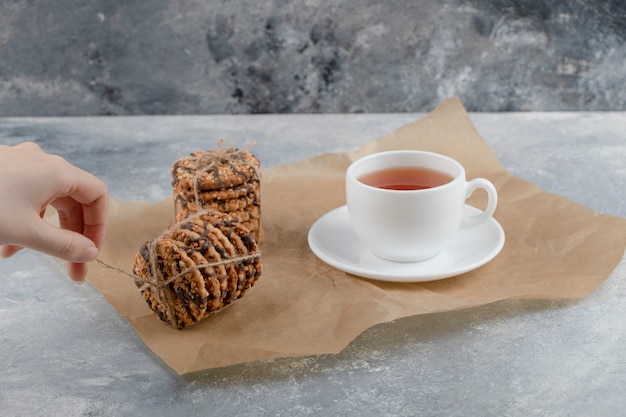 Female hand tying stack of biscuits on marble background.