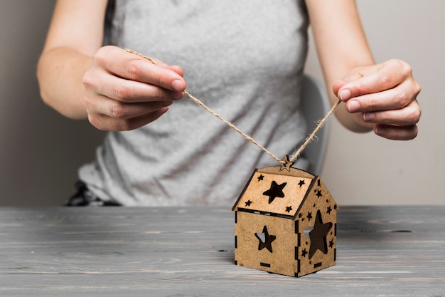 Female hand tying string on handmade brown house