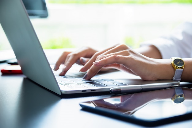 Female hand typing on keyboard of laptop