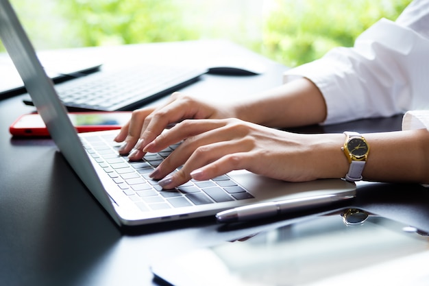 Female hand typing on keyboard of laptop