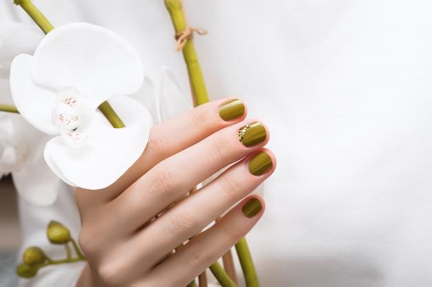 Female hand with green nail design, close up.