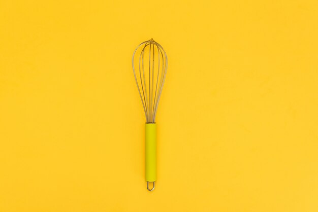 Premium Photo Female Hand With A Kitchen Whisk On Yellow Background