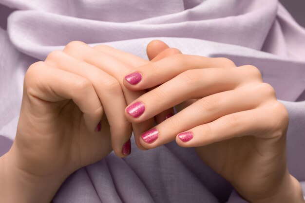 핑크 반짝이 네일 디자인으로 여성 손입니다.