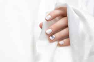 Free photo female hand with white dandelion nail design.