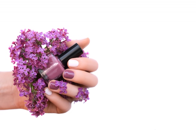 Free photo female hand with white and purple nail design holding lilac flowers