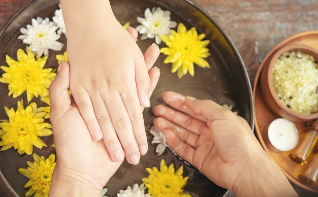 Female hands and bowl of spa water with flowers, close up. Hands Spa.