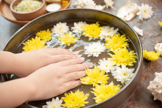 Free photo female hands and bowl of spa water with flowers, close up. hands spa.
