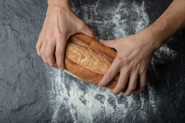 FeMale hands breaking freshly baked bread, closeup.