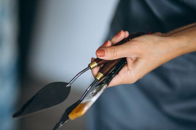 Female hands close up holding palette knife and art brush