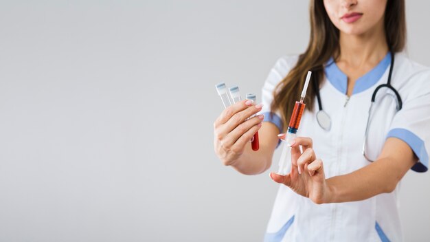 Female hands holding blood samples and a syringe