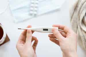 Free photo female hands holding electronic thermometer over the white offic