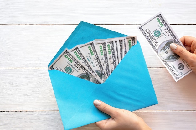 Free photo female hands holding an envelope with money, wooden background. finance idea