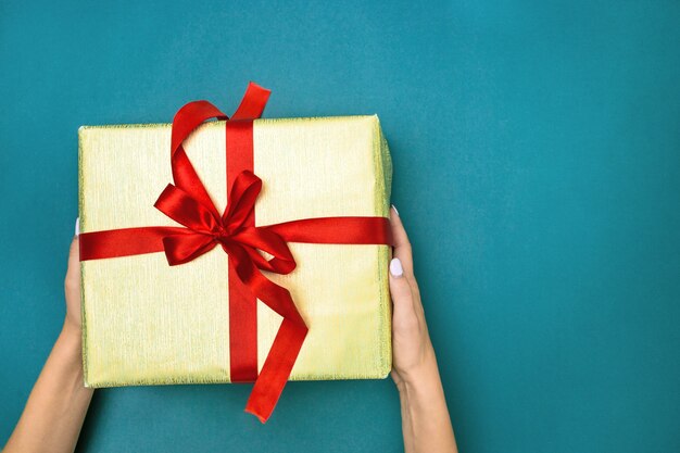 The female hands holding gift on blue background