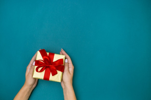 Female hands holding gift on blue background